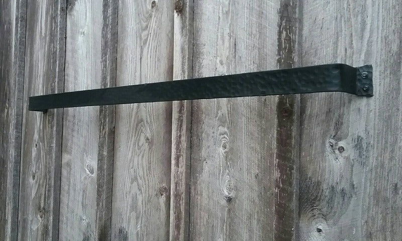 Angled view of 48" hand forged hammer finish pot rack. Shown without hooks. Made of 2" steel with black painted finish, mounted on a barn wood wall.